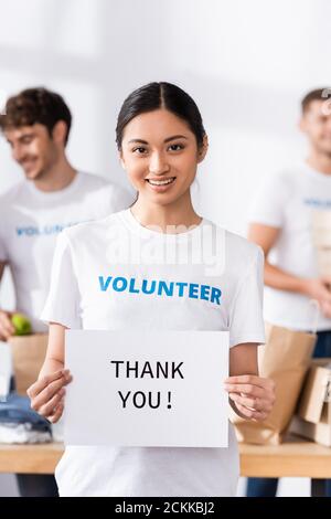Selektive Fokus der asiatischen Freiwilligen halten Karte mit danke Schriftzug im Charity Center Stockfoto