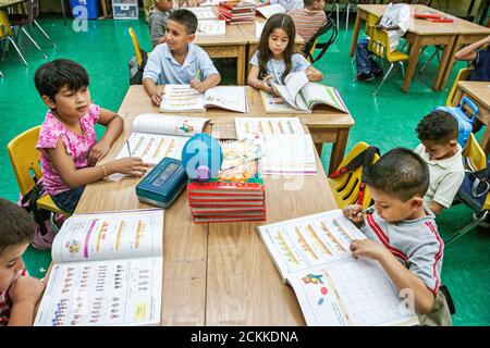 Miami Florida, Frederick Douglass Elementary School, Gemeinschaft mit niedrigem Einkommen, hispanische Studenten Mädchen jungen Klassenräume Schreibtische Arbeitsbuch lesen Stockfoto