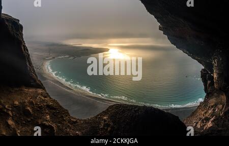 Aussichtspunkt über Famara Strand bei Sonnenuntergang mit bewölktem Himmel und Sonnenstrahlen aus den Wolken, Cueva de las Cabras, Lanzarote Insel, Kanarische Inseln, Sp Stockfoto