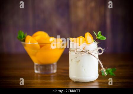 Hausgemachter süßer Joghurt mit Scheiben eingelegter Pfirsiche in einem Glasgefäß Stockfoto