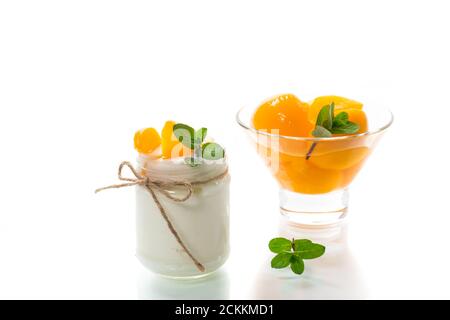 Hausgemachter süßer Joghurt mit Scheiben eingelegter Pfirsiche in einem Glasgefäß Stockfoto