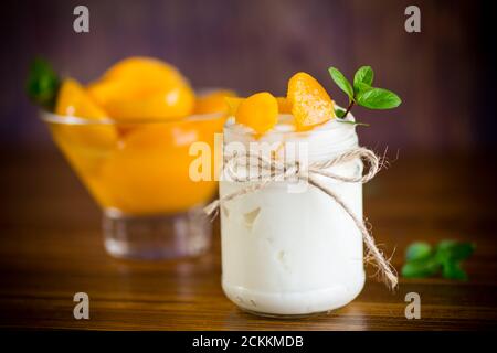 Hausgemachter süßer Joghurt mit Scheiben eingelegter Pfirsiche in einem Glasgefäß Stockfoto