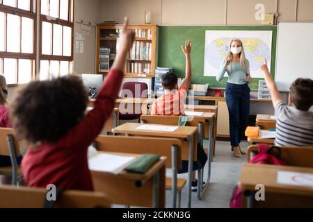 Gruppe von Kindern heben ihre Hände in der Klasse an Schule Stockfoto