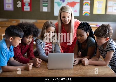 Weibliche Lehrerin und Gruppe von Kindern mit Laptop in der Klasse Stockfoto