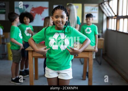 Portrait des Mädchens zeigt ihr Recycling T-Shirt in der Klasse In der Schule Stockfoto