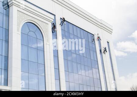 Vier Personen, Hochhauskletterer, waschen ein schönes Gebäude mit blauen Fenstern Stockfoto