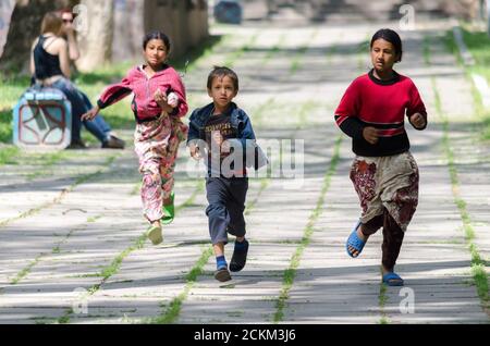 Drei Zigeunerkinder, ein Junge und zwei Mädchen laufen ihnen im Park entgegen. Kosmonauten-Park in Taschkent, 22. März 2019 Stockfoto