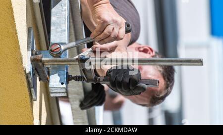 Schrauben und Festziehen einer Schraube mit Klemme und Ratschenschlüssel in Stahlkonstruktion. Mechanische Befestigung der Metallkonstruktion in Betonbaumauerwerk. Stockfoto