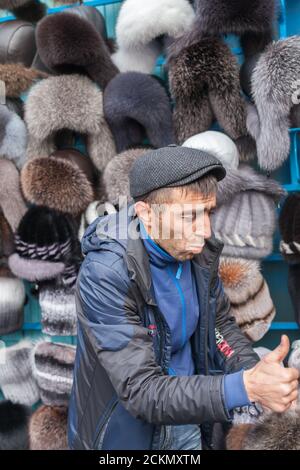 MURMANSK RUSSLAND - 2014. SEPTEMBER 14. Russischer Mann, der Winterhüte in Murmansk verkauft. Stockfoto