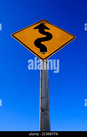 Kurven voraus auf Straßenschild Straßenschild hellgelb auf blau Himmel Stockfoto