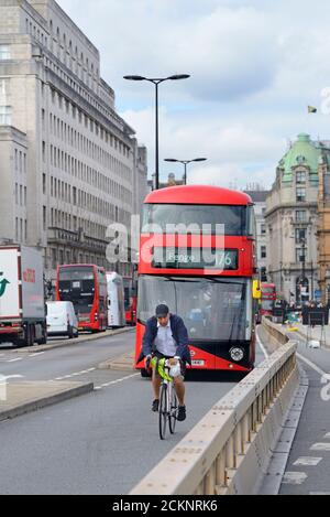 London, England, Großbritannien. Mann, der vor einem Bus über die Waterloo Bridge radelt Stockfoto