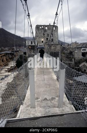 6. Dezember 1995 während des Krieges in Bosnien: Ein Mann überquert eine Seilbrücke, die die Stari Most (Alte Brücke) ersetzt, über den Fluss Neretva in Mostar. Stockfoto