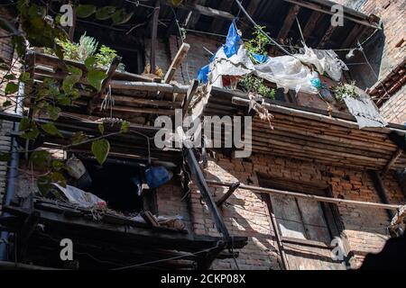 Blick auf die Straße von ein paar einfachen Balkonen aus Bambus mit Pflanzen, Kunststoff und Wäsche auf einem Backsteingebäude in Bhaktapur, Kathmandu, Nepal Stockfoto