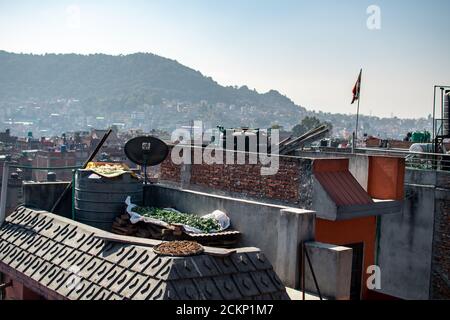 Bhaktapur, Kathmandu, Nepal - 23. Dezember 2019: Blick auf die Stadt von einem Dach über Obst und Gemüse, das in der Sonne trocknet und die Stadt im Hintergrund Stockfoto