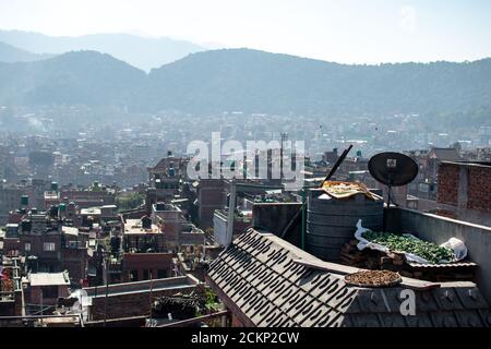 Bhaktapur, Kathmandu, Nepal - 23. Dezember 2019: Blick auf die Stadt von einem Dach über Obst und Gemüse, das in der Sonne trocknet und die Stadt im Hintergrund Stockfoto