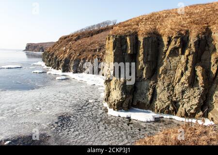 Eisschollen im Meer vor der wilden Felsküste von Cape Tobizin auf der russischen Insel in Wladiwostok. Stockfoto