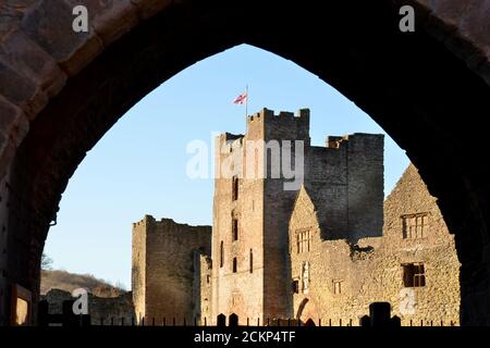 Nahaufnahme von Ludlow Castle, Shropshire Blick durch Torbogen. Die Flagge des Schlosses fliegt im Sommer gegen den blauen Himmel Stockfoto