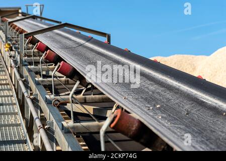 Nahaufnahme des Förderbandes im Betonwerk mit Transportrollen, sichtbare Metalltreppen. Stockfoto