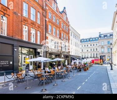 An einem sonnigen Tag können Sie sich am Straßenrand treffen, in der Fußgängerzone Henrietta Street, Covent Garden, London WC2 speisen, essen und trinken Stockfoto