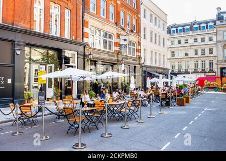 An einem sonnigen Tag können Sie sich am Straßenrand treffen, in der Fußgängerzone Henrietta Street, Covent Garden, London WC2 speisen, essen und trinken Stockfoto