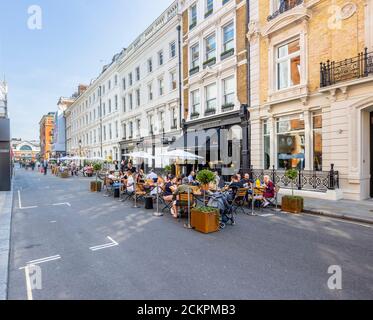 An einem sonnigen Tag können Sie sich am Straßenrand treffen, in der Fußgängerzone Henrietta Street, Covent Garden, London WC2 speisen, essen und trinken Stockfoto