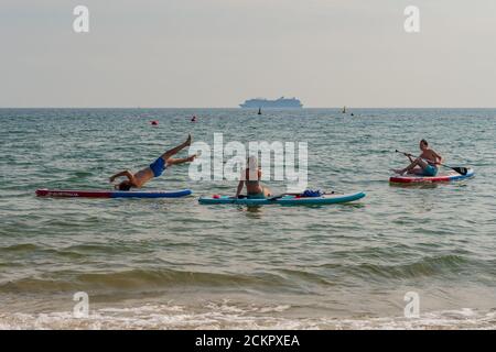 Boscombe, Bournemouth, Dorset, UK, 16. September 2020, Wetter. Menschen am Strand und im Meer genießen den dritten Tag der September Hitzewelle mit heißem Sonnenschein am Nachmittag. Ein Paddlebarder versucht etwas Akrobatik auf seinem Brett und versucht einen Handstand, schließlich fallen. Kredit: Paul Biggins/Alamy Live Nachrichten Stockfoto