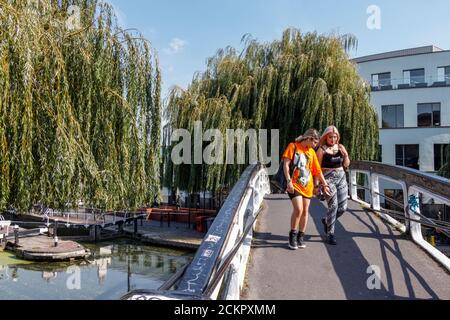 Zwei junge weibliche Touristen, die während einer Mini-Hitzewelle im September die Fußgängerbrücke am Camden Lock überquerten, London, Großbritannien Stockfoto