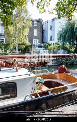 Ein Segelschiff, das in der Primrose Hill Gegend des Regent's Canal festgemacht ist, eine Replik einer Kuh in voller Größe auf dem Balkon eines Hauses gegenüber, London, Großbritannien Stockfoto