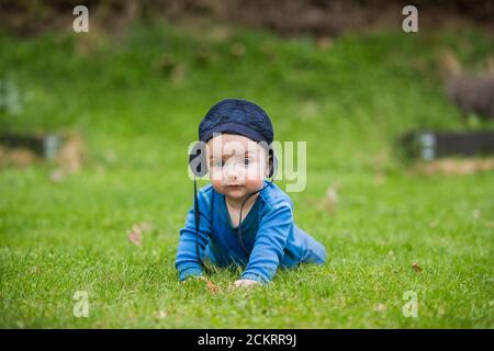 6 Monate altes Baby kriecht draußen im grünen Gras Stockfoto