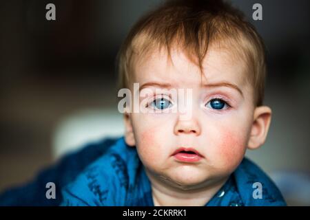 Nahaufnahme eines 6-8 Monate alten Jungen, der geradeaus blickt Mit einem aufrichtigen Ausdruck Stockfoto