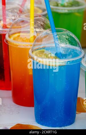 Bunte kalttönende Cocktails in Plastikbechern mit Cocktail-Trinkhalmen Stockfoto