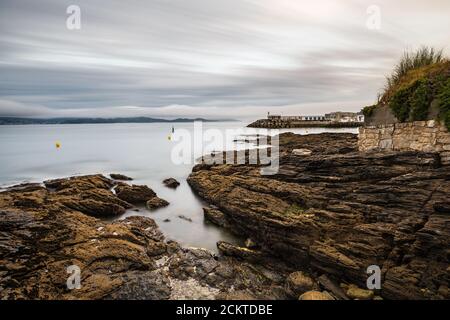 Felsen und kleiner Leuchtturm an einem stürmischen Abend in den Rias Baixas in Galicien, Spanien. Langzeitbelichtung. Stockfoto
