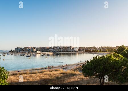 PORTONOVO, SPANIEN - 7. AUGUST 2020: Weitwinkelansicht des Strandes und Sporthafens von Portonovo in der Ria de Pontevedra in der Abenddämmerung, Spanien. Stockfoto