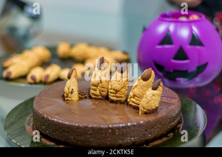 Halloween Schokoladenkuchen Feier mit geriffelten Cookies Finger und Hintergrund Lila Kürbis und Teller mit Fingern Stockfoto