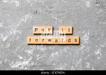 Pay IT Forward Wort auf Holzblock geschrieben. Pay IT Forward Text auf Zementtisch für Ihr Design, Konzept. Stockfoto