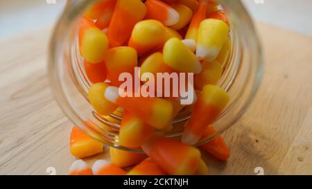 Nahaufnahme von Zuckermais, die aus einem verschüttet werden Glas auf einer hölzernen Arbeitsplatte Stockfoto