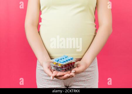 Nahaufnahme von Haufen Blasen von Pillen in der Hand der schwangeren Frau auf bunten Hintergrund mit Kopierraum. Gesundheitsversorgung und Behandlung während der Schwangerschaft conce Stockfoto