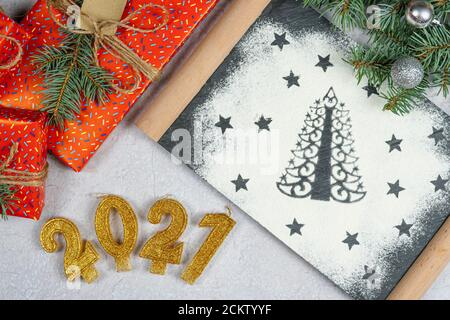 Silhouette von Weihnachtsbaum aus Mehl. Feiertagshintergrund mit dem Text der goldenen Zahl 2021, Geschenkbox und Baumzweig, Draufsicht. Konzept von Stockfoto