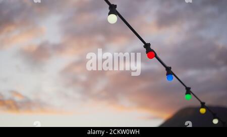 Girlande auf einem Hintergrund von Sonnenuntergang und Berge. Elemente der Strand Hochzeit Dekoration, Partys. Lampen und Herzen hingen an einem Seil gegen das Meer. Stockfoto