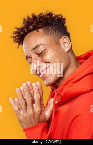 Junger Erwachsener lächelt weit und hält die Handflächen zusammen Stockfoto