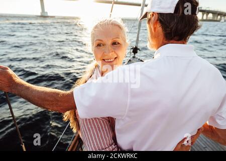 Porträt einer lächelnden reifen Frau umarmt ihren Mann und Wegschauen Stockfoto