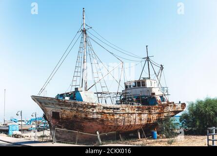 Altes rostiges Fischerboot, das an Land in der Nähe des Meeres steht Stockfoto