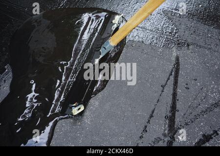 Mann versiegelt Asphalteinfahrt/Sealcoating Stockfoto