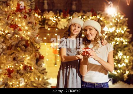 Tochter gibt ein Geschenk in einem Zimmer zu Weihnachten. Stockfoto