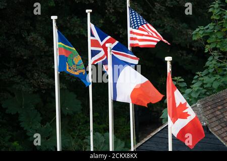 Fünf internationale Flaggen, die auf den Pfählen fliegen, darunter Union Jack, amerikanische, französische und kanadische Flaggen Stockfoto