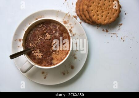 Draufsicht auf einen Tisch, wo wir eine Schüssel sehen Von Milch mit löslichem Kakao neben etwas Vollkorn Cookies Stockfoto