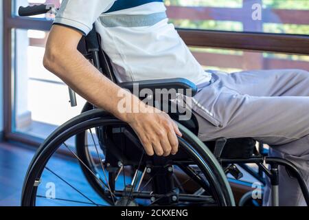 Mann im Rollstuhl zu Hause oder im Büro. Konzentriere dich auf seine Hand. Stockfoto