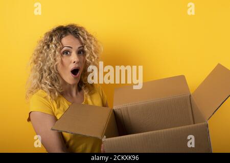Glückliche Frau erhält ein Paket von Online-Shop bestellen. Gelber Hintergrund. Stockfoto