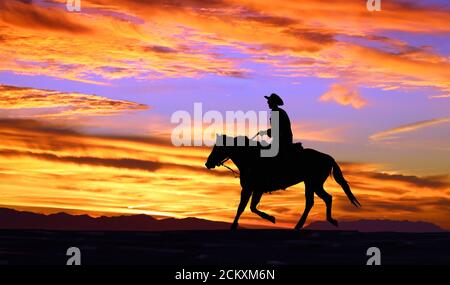 Cowboy auf einem Pferd silhouetted gegen den Sonnenuntergang Stockfoto