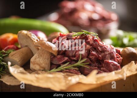 Geschnittenes Hirschfleisch, das für den Eintopf von Waldpilzen zubereitet wird Kräuter und Gemüse Stockfoto